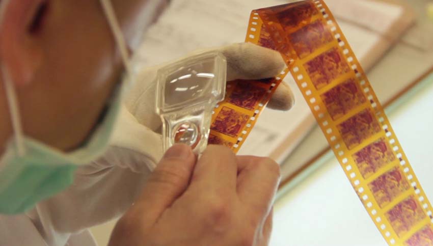 Visually inspecting films with the aid of magnifying lens